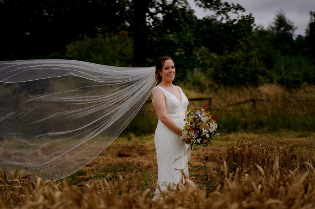 bride with veil in field at lodge farm wedding venue cundall