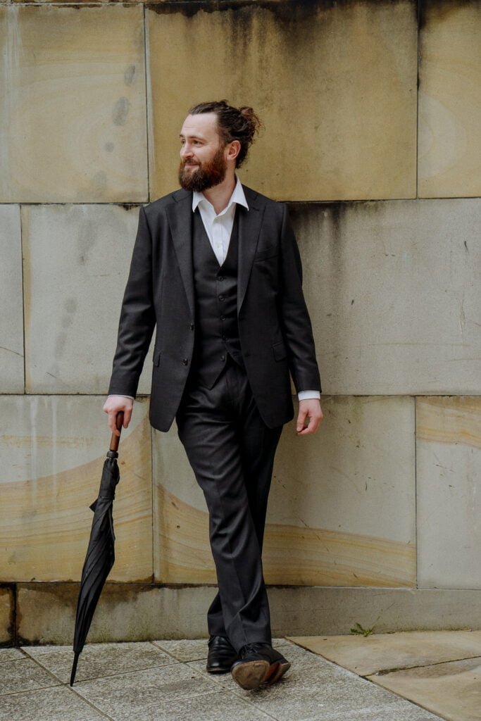 groom in dark suit and umbrella